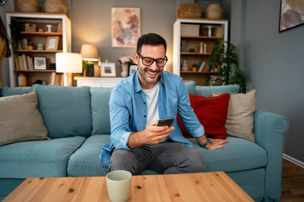 istock Young cheerful man using phone at home 2195719423