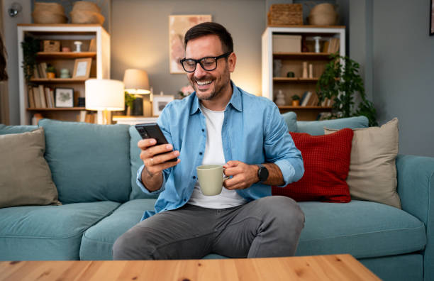 istock Young cheerful man using phone at home 2195719544