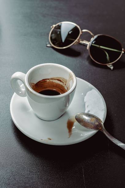 Espresso cup and sunglasses on table.