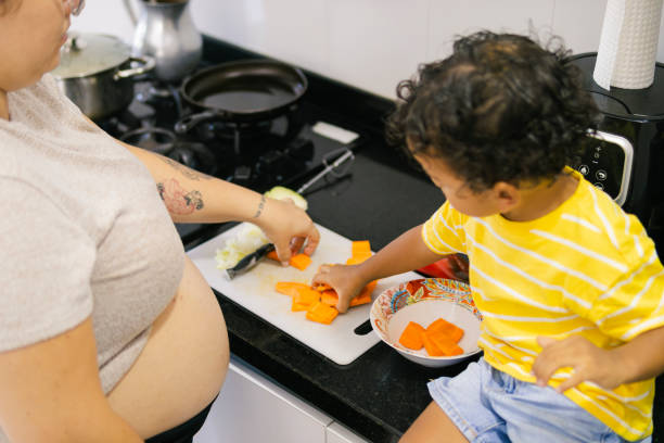 istock Pregnant mother and son preparing vegetables in kitchen 2195721177
