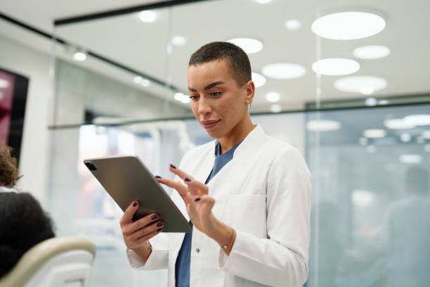 istock Cheerful Female Dentist Using Digital Tablet in Clinic 2195721607