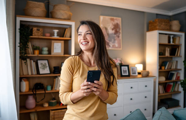 istock Woman with phone looking through the window 2195721756