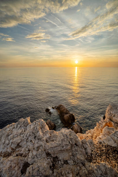 istock Sunset over calm ocean waters near rocky coastline 2195724963