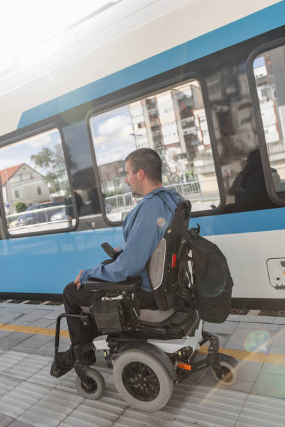 istock Man with a physical disability, an electric wheelchair user entering a train 2195725079