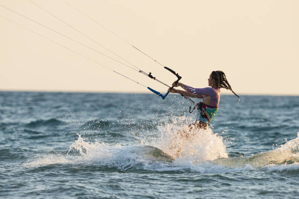 Woman  on solo travel riding kitesurf dring golden hour
