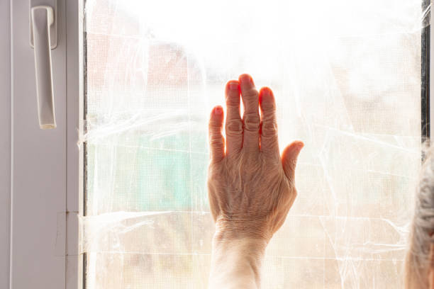 istock An elderly woman's hand on a window that is sealed with adhesive tape as protection from shrapnel during an explosion, a hand 2195734784