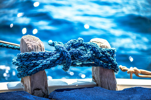 Wooden walkway features blue railing and rope, leading to calm water, evoking a peaceful ambiance for relaxation and leisure by the beach during sunset