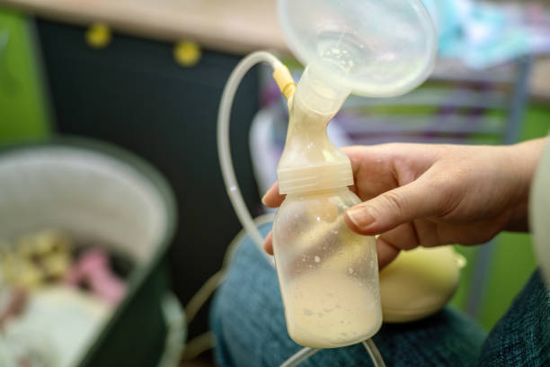 istock woman's hand holds a breast milk pump with a funnel, designed for automatic milk extraction, alongside a bottle filled with milk for newborn feeding 2195741643