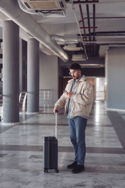 istock Young man waiting at the airport and using his smartphone 2195743364