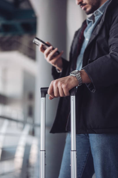istock Businessman using smartphone and holding suitcase at airport 2195743676