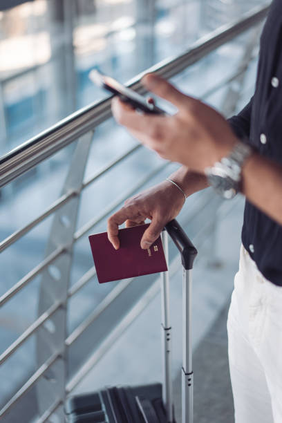 istock Businessman using smartphone and holding passport at airport 2195745063