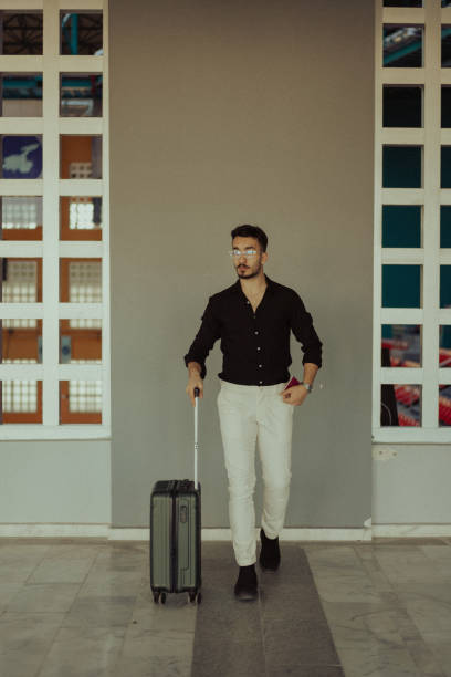 istock Stylish businessman pulling suitcase at the airport 2195746111