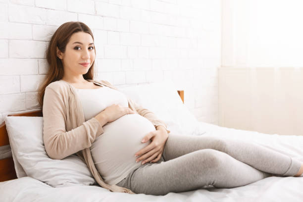 istock Happy pregnant lady caressing her belly, lying in bed 2195746391