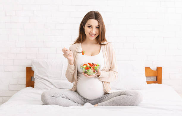 istock Cheerful expectant girl enjoying fresh vegetable salad 2195746448