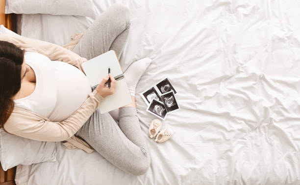 istock Pregnant woman making notes in notebook and holding ultrasound 2195746500