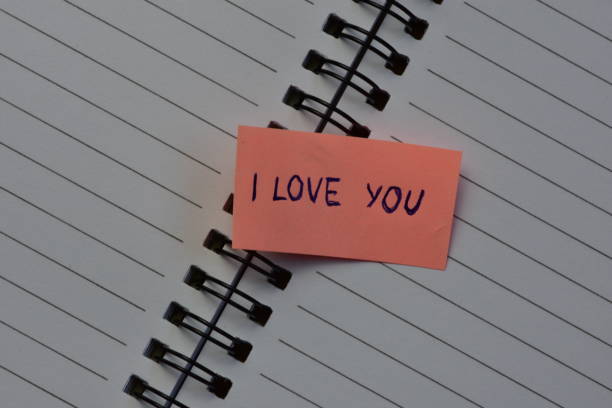 istock Message I love you on pink sticky note for valentines day on spiraled notebook open pages background 2195748722