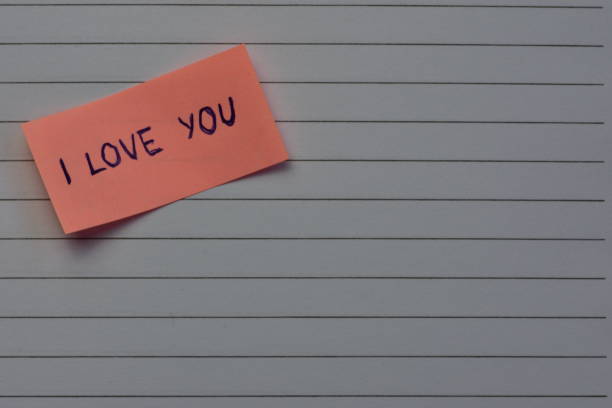 istock Message I love you on pink sticky note for valentines day on notebook line paper background 2195748765