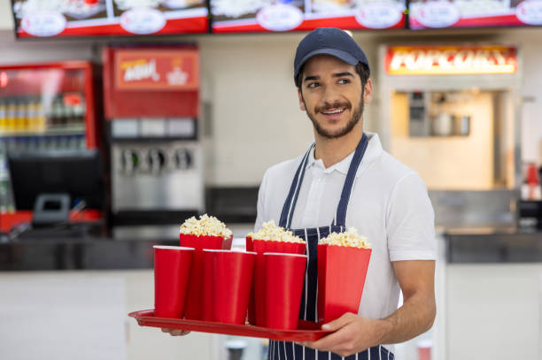 istock Retail clerk working at a concession stand and holding popcorn and drinks 2195751156