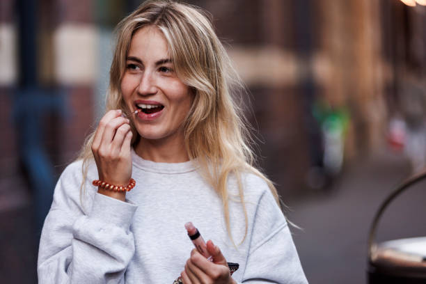 Cute girl putting on lip gloss