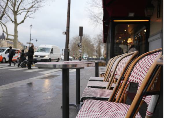 istock Rainy Paris street with empty wicker cafe chairs and table outside a bistro 2195758055