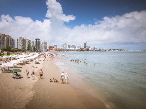View of Punta del Este city from the pier at the Mansa beach. People enjoying at the beach. Beachfront holiday rentals and hotels.