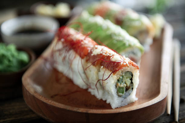 Sushi rice roll wrapped in a wooden plate.