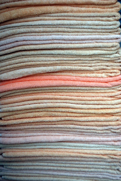 A close-up of a neatly stacked collection of towels in soft pastel hues of tan, pink, salmon, and white. The delicate textures and serene colors evoke a sense of luxury and relaxation, perfectly complementing the tranquil atmosphere of Cancún, Mexico. This image captures the subtle elegance of tropical comfort.