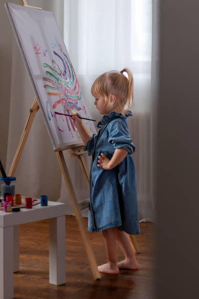 istock Little girl drawing a picture on canvas on an easel 2195770193