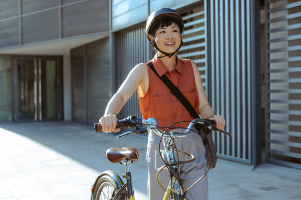 istock Smiling Japanese female commuter with a bicycle outside a modern building 2195773469