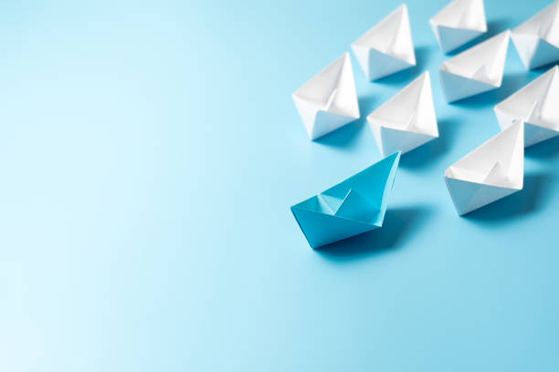 istock Leadership concept with blue paper ship leading among white 2195776295