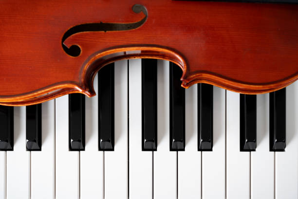 istock Violin on top of piano keyboard background 2195776375