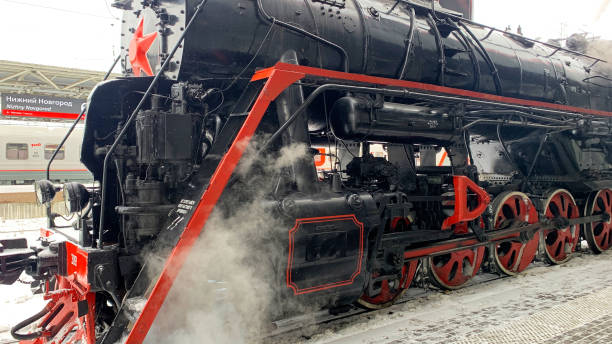 istock Steam train with red and black wheels is sitting on a snowy platform 2195781882
