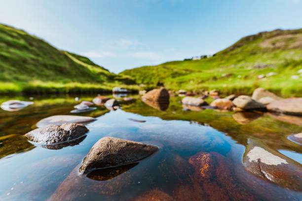Peaceful stream flowing through the green hills of isle of skye, scotland, on a sunny summer day