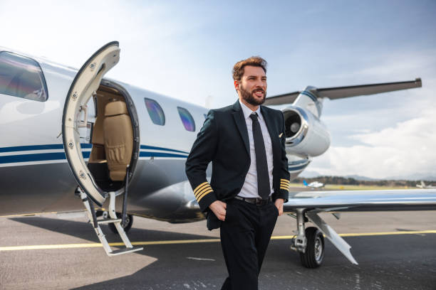 istock Confident Pilot Standing by Private Jet at Airport 2195789401