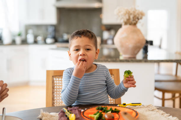 istock Young boy eating broccoli at the dinning table 2195791473