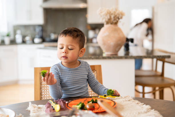 istock Young boy eating broccoli at the dinning table 2195791474
