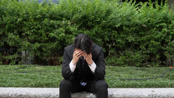 businessman holding his head outside - 不安障害 ストックフォトと画像