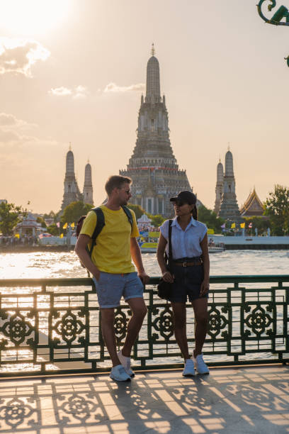 istock Couples stroll along the riverside in Bangkok as the sun sets behind Wat Arun 2195797919