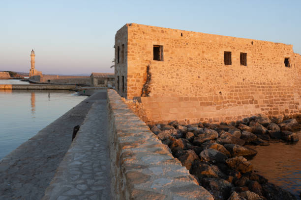 Medieval bastion on Lighthouse walk at Chania illuminated with golden hue at sunrise on island of Crete.