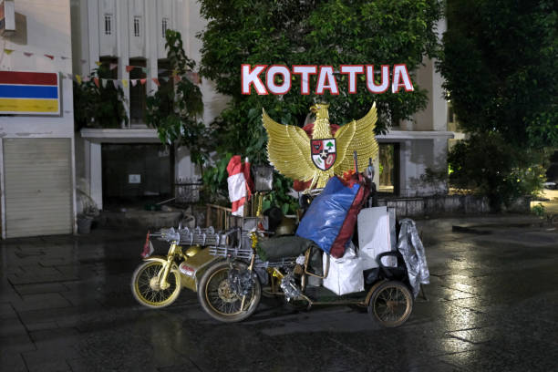 Motorized tricycle with emblems and Kota Tua name at night in Taman Fatahillah square, Jakarta, Indonesia.