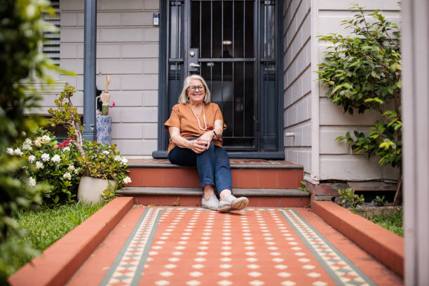 istock Senior woman sitting alone on porch step 2195802775