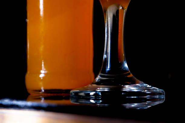 A glass and bottle of orange drink in low light