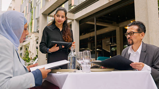 istock Asian Couple Discussing Menu with Waitress at Indian Restaurant 2195808606