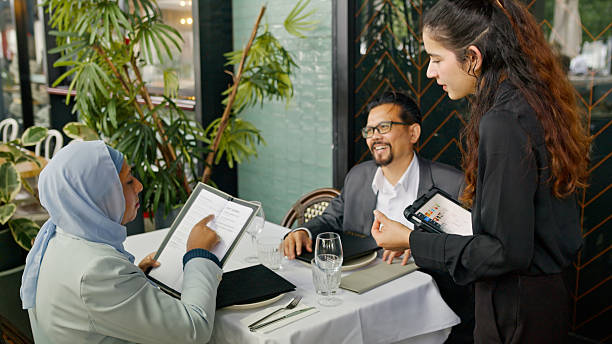 istock Asian Woman Looking at Menu while Husband and Waitress Look on 2195808620