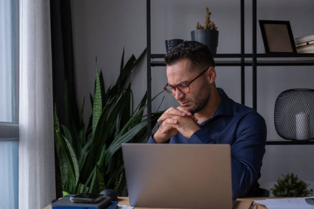 istock Pensive businessman working from home office looking at laptop screen 2195808803