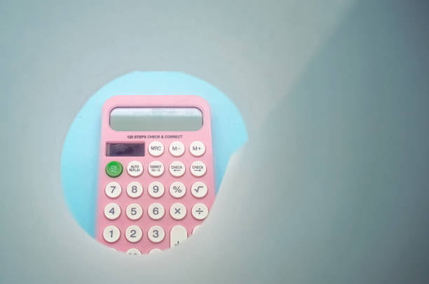 istock A pink calculator with white buttons is viewed through a circular cutout. The calculator is placed on a light blue background, creating a unique and creative composition 2195811075