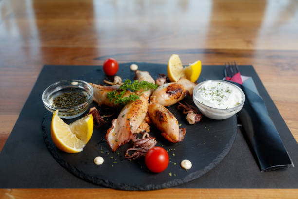 istock Grilled Squid with Lemon and Dipping Sauces on Slate Plate 2195813430