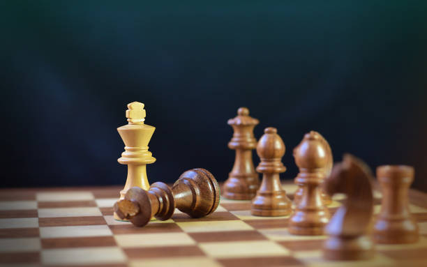 Last move in chess, check mate, brown king chess piece fallen down defeated, over black background