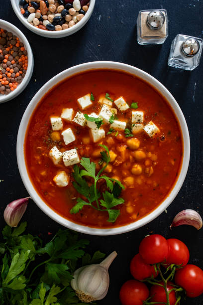 Lentil and tomato soup with feta cheese on black table
