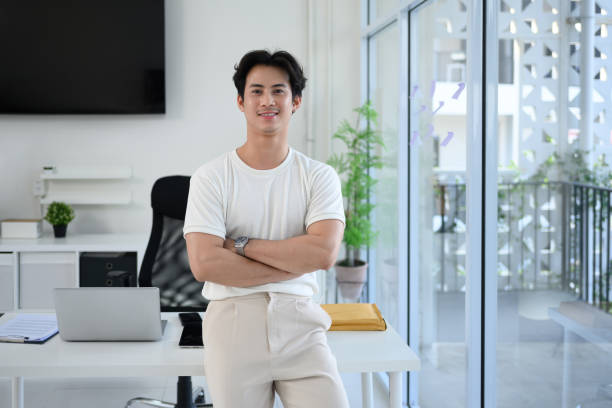 istock Confident young entrepreneur standing with arms crossed in a bright modern office 2195816938